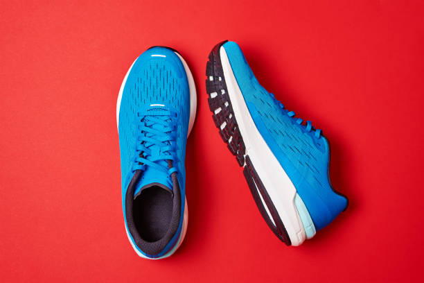 istock Pair of blue running sneakers on red background, top view 1350560630