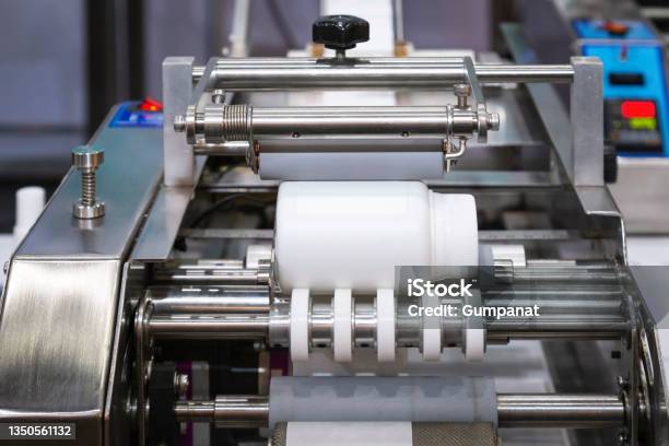 White Plastic Bottle On Small Tabletop Bottle Sticker Labeling Machine For Medicine And Pharmaceutical Industry Stock Photo - Download Image Now