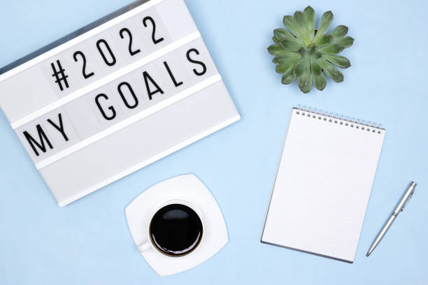 istock Aspirations and plans for the coming 2022 year concept. Notebook, pen, coffee cup, succulent, lightbox with My Goals text on blue desk. Office workplace - top view 1350566852