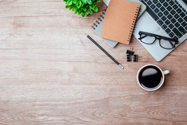 istock Work from home. desk office with laptop, blank notepad, coffee cup and pen on wood table. Flat lay top view copy spce. 1350567156