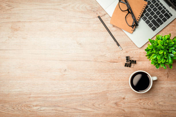 istock Work from home. desk office with laptop, blank notepad, coffee cup and pen on wood table. Flat lay top view copy spce. 1350567172