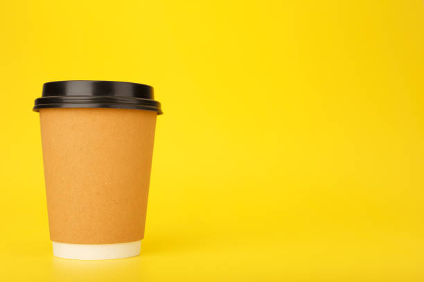 istock Minimal composition with brown cardboard cup of coffee on yellow background with copy space 1350569749