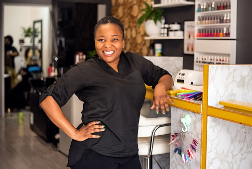 Portrait of a smiling young woman manicurist standing in manicure salon