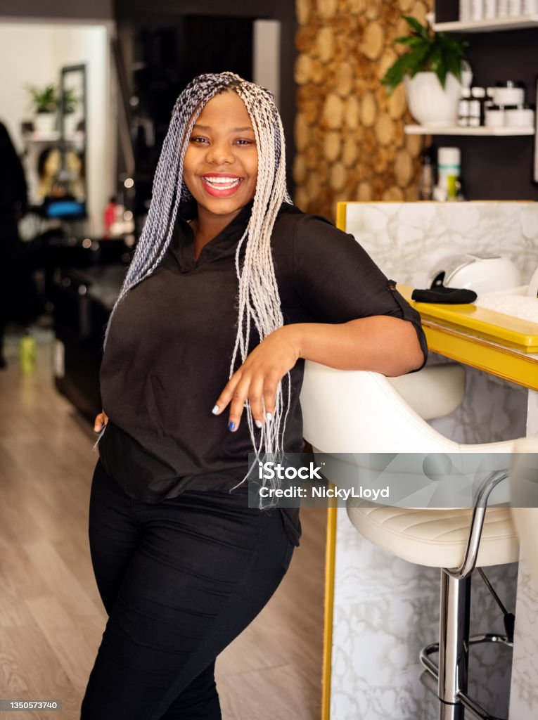 Portrait of a successful beautician in her beauty salon Portrait of a successful beautician with box braids standing in her beauty salon looking at camera and smiling Hairdresser Stock Photo