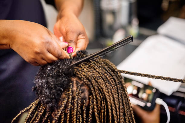 African hairstyle with hair extension Close-up of a hairstylist hands making braids and doing hair extension to her client in salon black woman hair extensions stock pictures, royalty-free photos & images