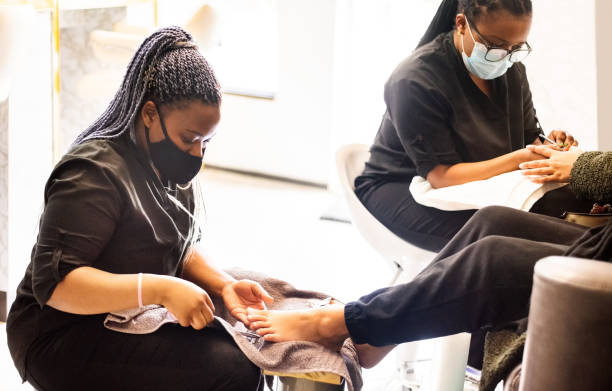 Woman having pedicure and manicure at beauty spa during pandemic stock photo