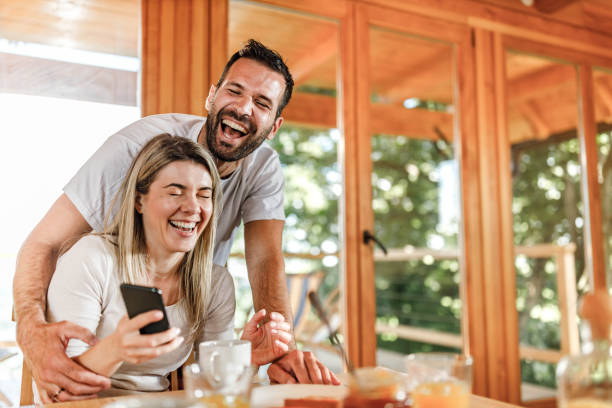 istock Cheerful couple using mobile phone during breakfast in the morning. 1350578169