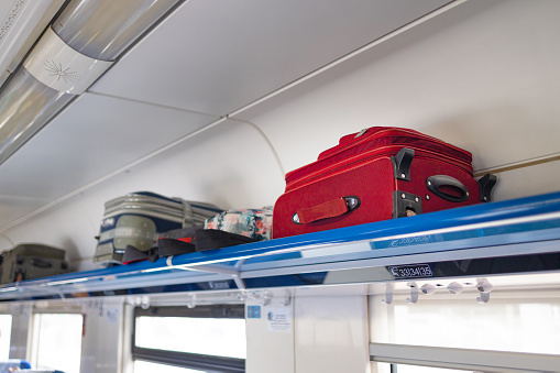 Traveler and tourism suitcases stacked in the luggage compartment of a train
