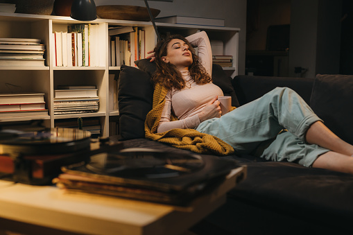 woman relaxing on sofa at her home listening records