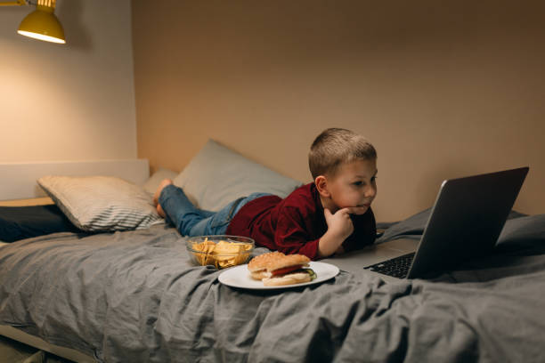 little boy at home young boy eating unhealthy food and using computer terrible meal stock pictures, royalty-free photos & images