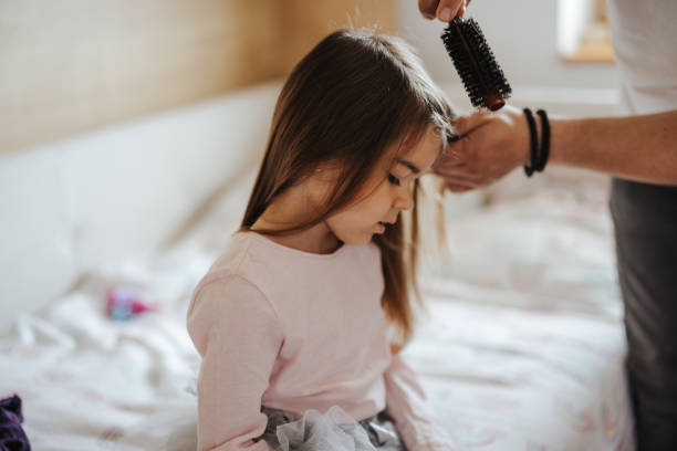 Father brushing his little daughter's hair at home