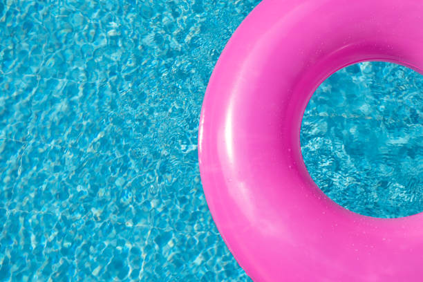 istock Summer background with pink inflatable ring donut in blue swimming pool. Top view. Copy space. Hot sunny vacation concept 1350581245