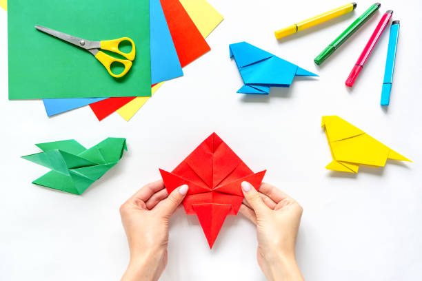 istock Human hands make origami from paper on a white background. Children's creativity. Back to school 1350581979