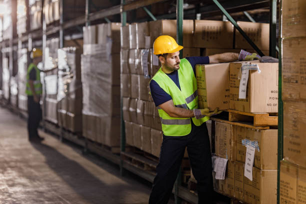 istock Young warehouse worker working cardboard boxes in industrial building. 1350582056