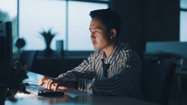 Businessman looking stressed during a late night in a modern office Asian young businessman experiencing stress during a late night at work. emotional series stock pictures, royalty-free photos & images