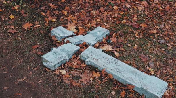 crucifix en béton de pierre brisé dévasté en acte de haine religieuse et de persécution laissé sur le sol amoung feuilles de feuillage d’automne fléties - vandalism photos et images de collection