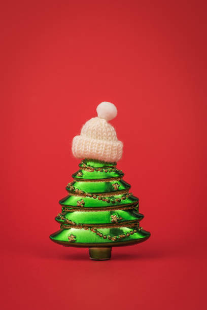 istock Creative green spruce in a knitted white hat on a red background. 1350583414