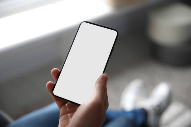istock Man holding mobile phone with empty screen indoors, closeup 1350583690