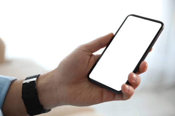 istock Man holding mobile phone with empty screen indoors, closeup 1350584098