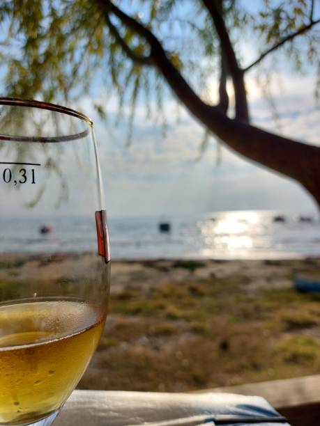 istock Beer glass on table in front of a tree by the seaside 1350592548