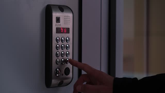 Male opens electronic code lock. man hand entering security system code, pressing button with index finger on modern intercom device with blue lcd screen near entrence door