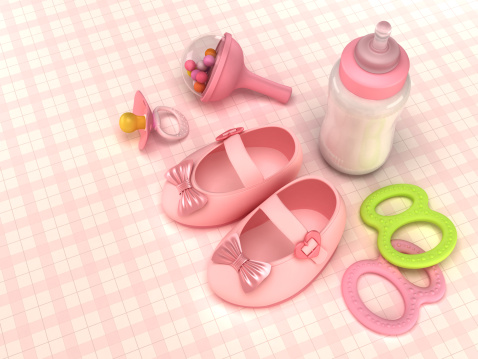 Baby shoes, pacifier, feeding bottle, rattle and toys standing on the table. All in pink tones... Extra space for text.