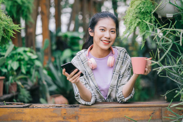 femme asiatique dans le jardin - fresh coffee audio photos et images de collection