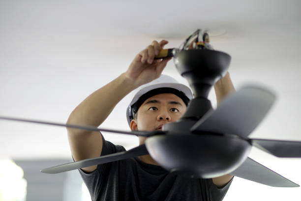 Electrical Services An Asian man is changing ceiling fan at residence. ceiling fan stock pictures, royalty-free photos & images