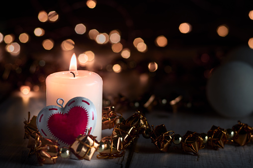 Lighted candle with a heart and Christmas ornaments