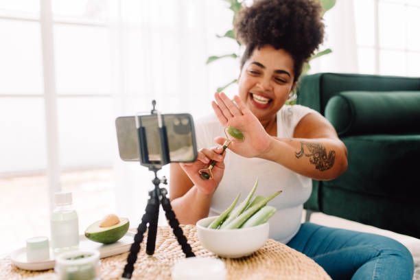 woman vlogging how to use jade roller on skin - influencer stockfoto's en -beelden