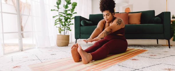 Healthy female doing fitness training at home Woman doing yoga exercise at home while sitting on yoga mat. Fitness female in exercise outfit stretching at home. touching toes stock pictures, royalty-free photos & images