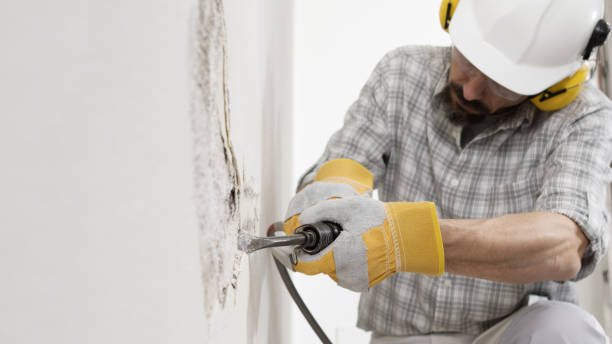 concept de rénovation de maison, ouvrier de la construction casse le vieux plâtre du mur avec un ciseau à marteau pneumatique, porte des gants, un casque et des écouteurs jaunes de sécurité, gros plan avec un espace de copie blanc - breaking wind audio photos et images de collection