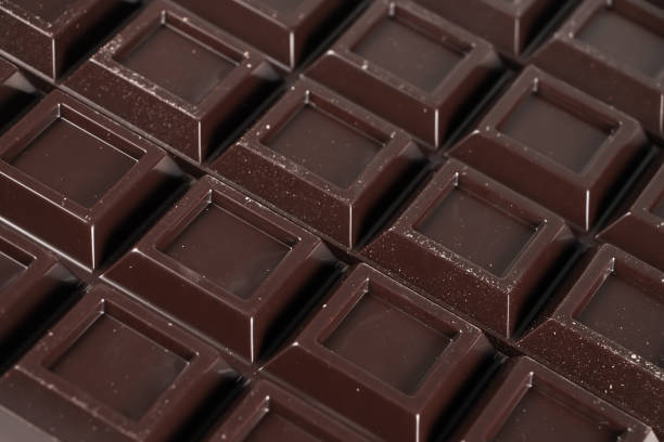 istock Close up a chocolate bar background. Chocolate bar cubes macro 1350613776