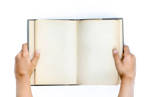 istock Two hands hold blank book. Open vintage empty diary in hands of child. Isolated on white, top view. 1350613990