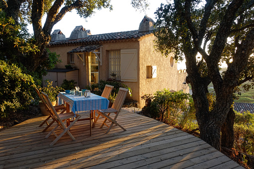 Country house in the south of France in the evening light. Terrace with set table.