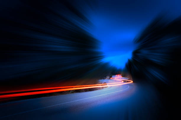 カーブアスファルト、夜の山道、長時間露光で夜に車のライトトレイル - land vehicle in a row action motion ストックフォトと画像
