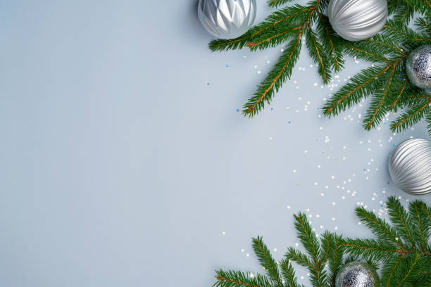 istock Silver Christmas decorations, green fir tree branches, star confetti on light blue background. Festive winter holiday template for advertising. Seasonal sale mockup. Flat lay, copy space, top view 1350617550