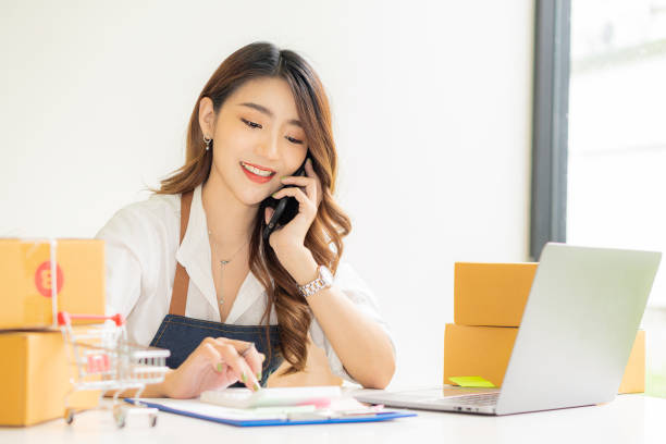 istock Young woman working at home with box and laptop taking orders from customers online work concept sme ready to deliver parcels 1350617686