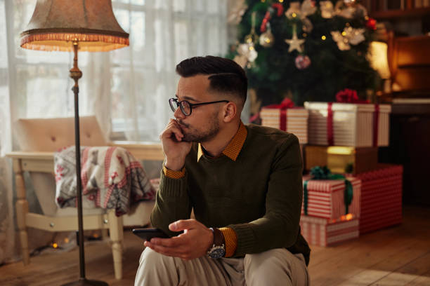 Lonely man using phone at Christmastime stock photo