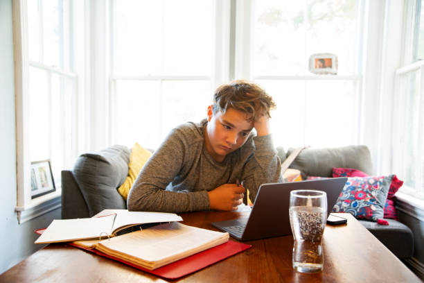 A teen taking online lessons or doing homework at home A teen student taking online lessons or doing homework at home boring homework twelve stock pictures, royalty-free photos & images