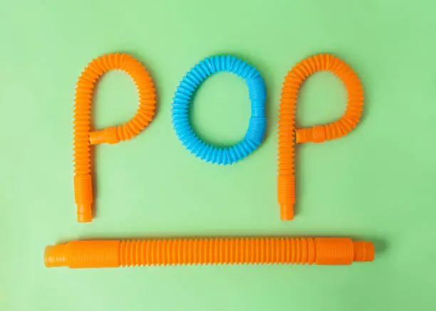 Photo of Composition from antistress toys - pop tubes.Word pop and tube under it.Funny finger game.