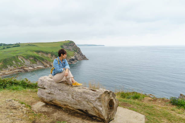 istock Cheerful caucasian woman isolated sit on a cliff bench. 1350624458