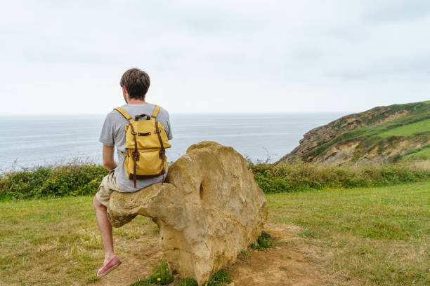 istock Adventurous caucasian man isolated sit on a cliff bench. 1350624476