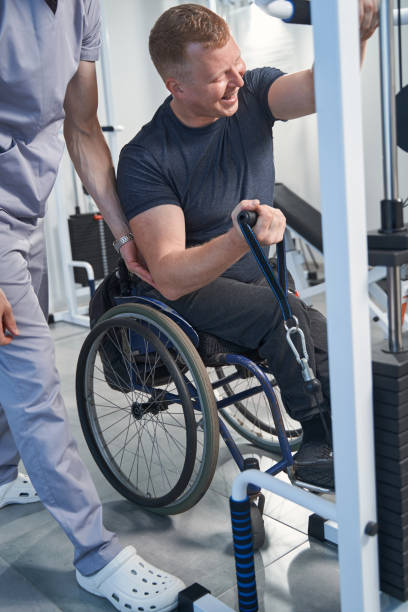 istock Young man with sport injury exercises with weight on tether machine 1350626403