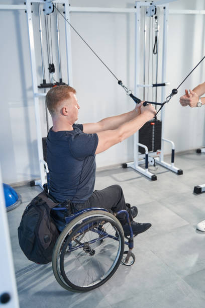 istock Man with disability exercises with resistance band in therapy room 1350626406
