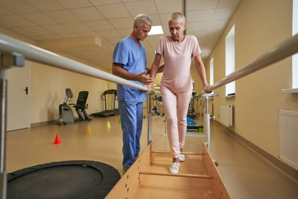 istock Female patient walking between parallel bars at rehabilitation room 1350626486