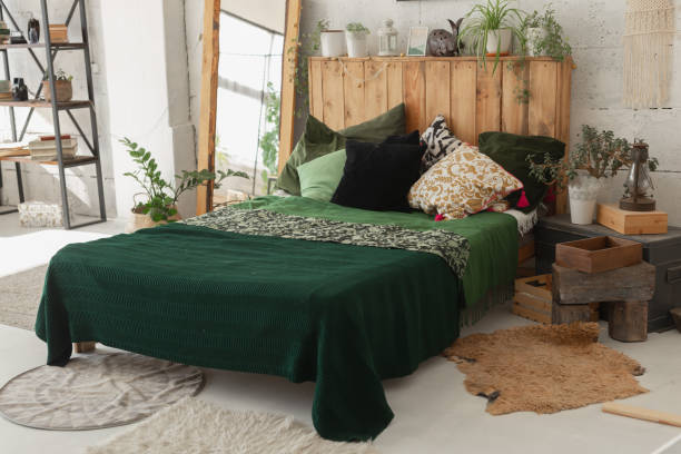 istock Comfortable bed with new green linens in eco style room interior 1350626488