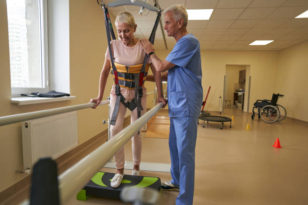 istock Mature woman walking between parallel bars at rehabilitation room 1350626501