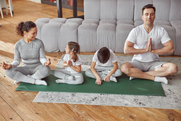 istock Cheerful parents teaching kids doing meditation at home 1350627100