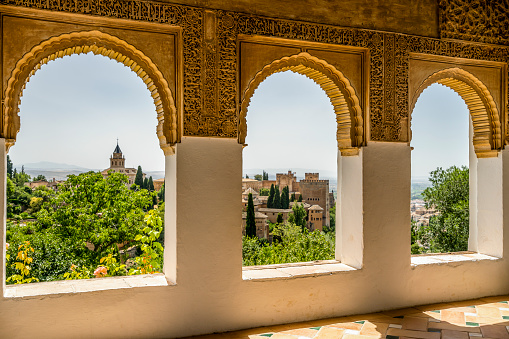 View of Nasrid Palaces through arches of Generalife Palace in Alhambra in Granada, Spain